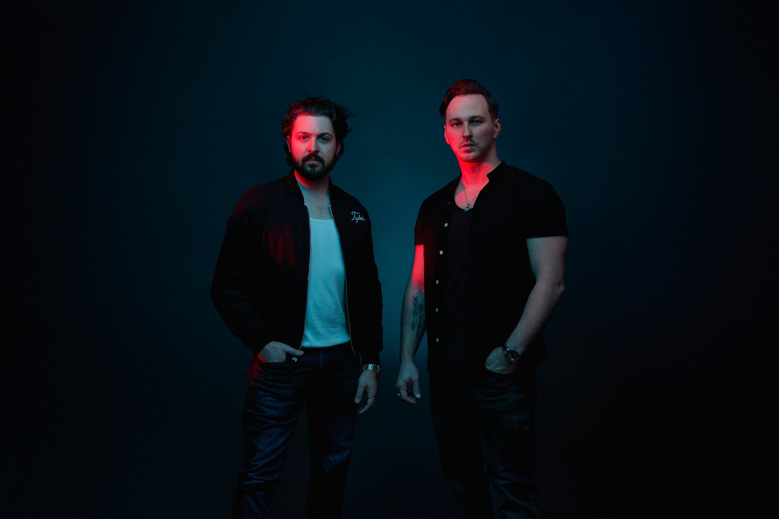 Coupe Marra, Tyler Anderson and Chris Jackson, standing against a dark teal backdrop in red light